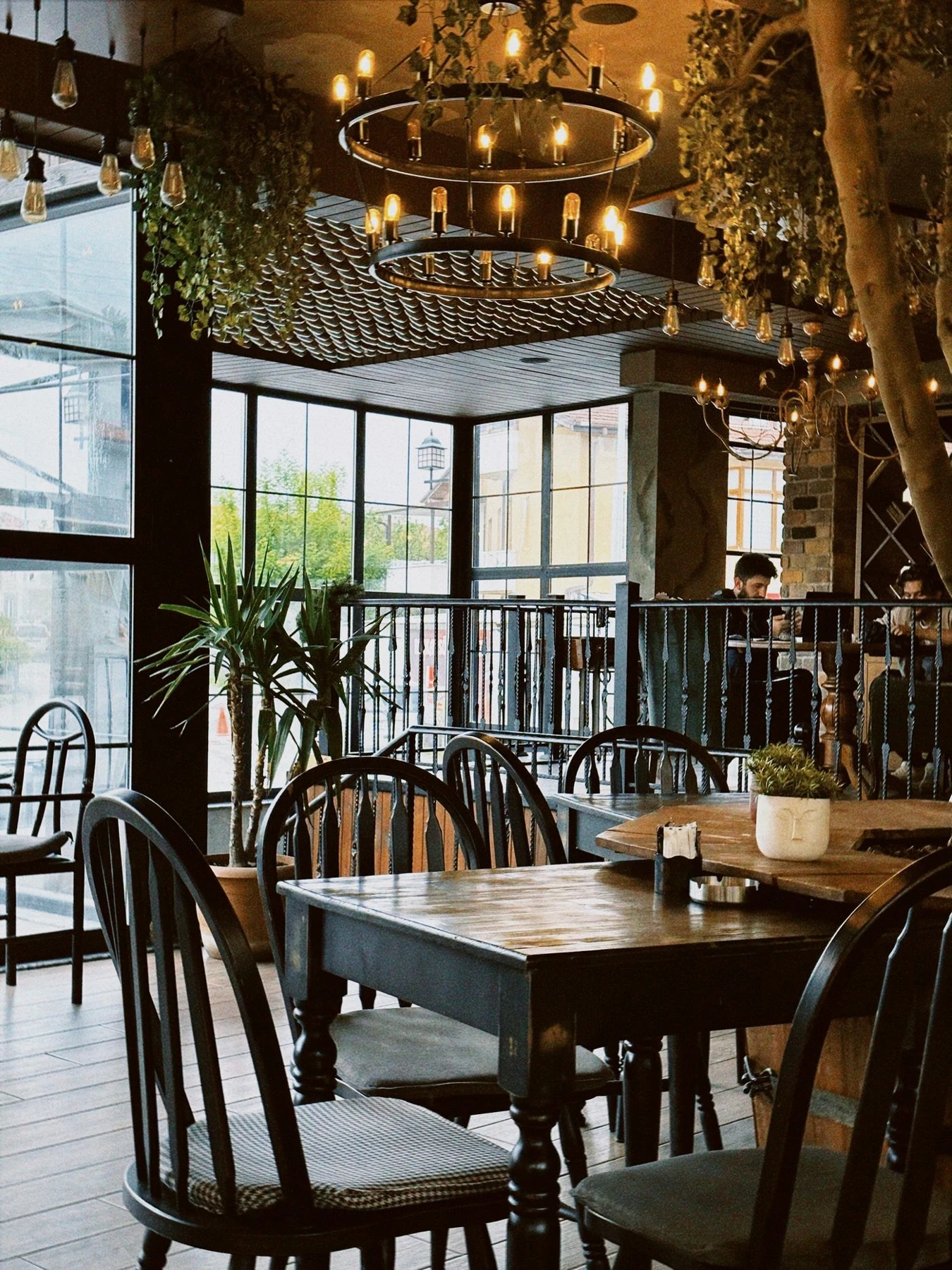 Warm restaurant dining room with wooden tables and window light.